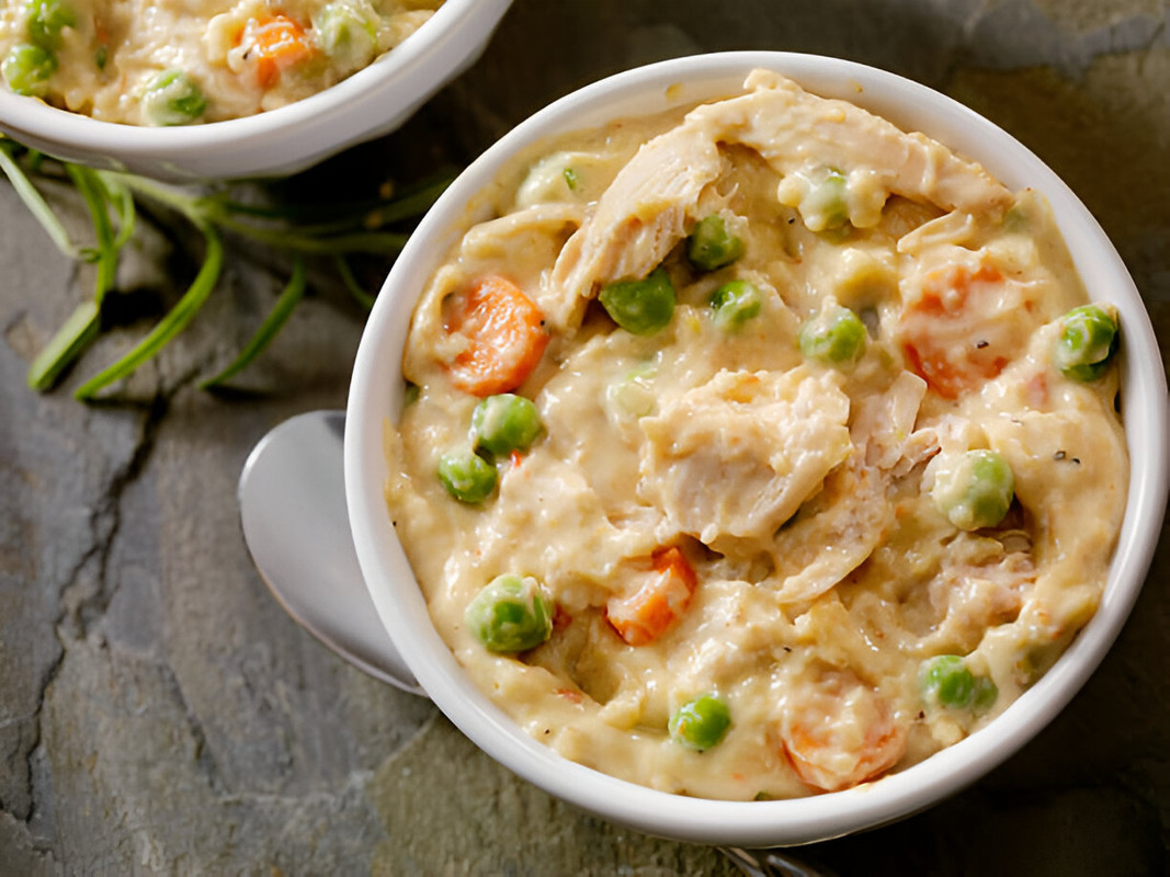 A bowl of creamy chicken and vegetable stew with peas and carrots