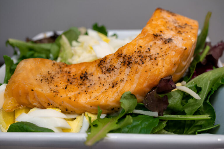 Grilled salmon fillet served on a bed of mixed greens and vegetables.