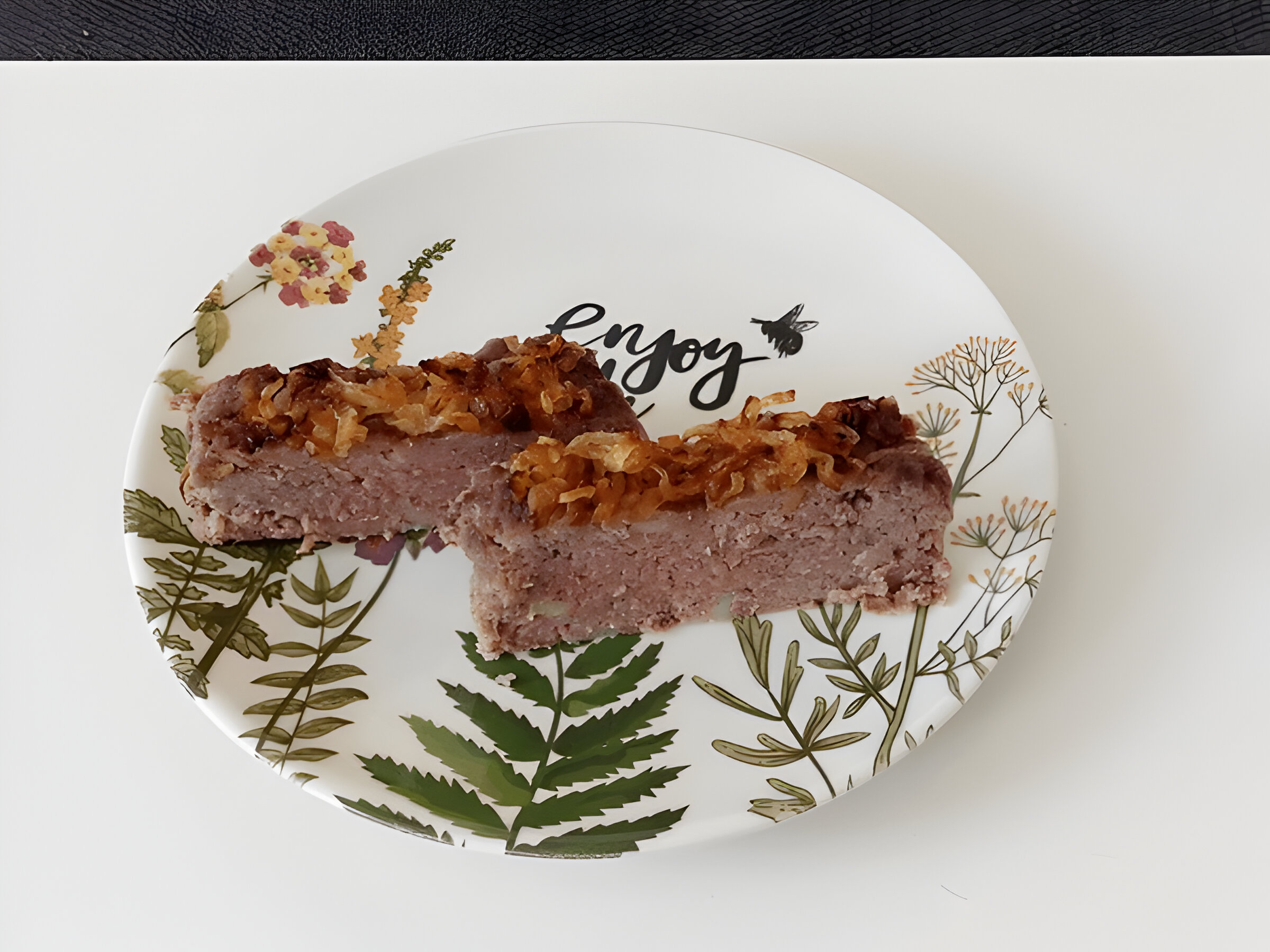 Two pieces of meatloaf topped with caramelized onions on a decorative plate.