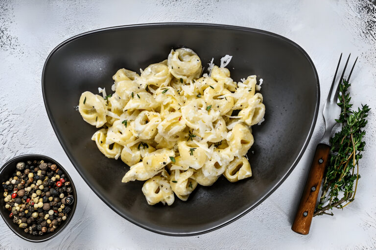 A bowl of creamy pasta served with herbs and black pepper