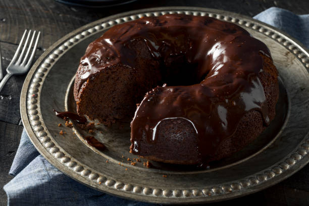 A chocolate glazed bundt cake on a decorative silver platter