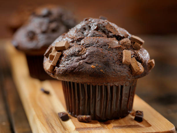 Delicious chocolate muffin topped with chocolate chunks on a wooden board