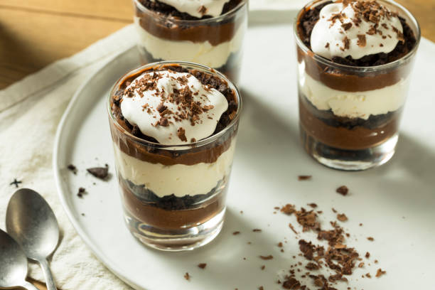 Delicious chocolate dessert layered in glass cups topped with whipped cream and chocolate shavings.