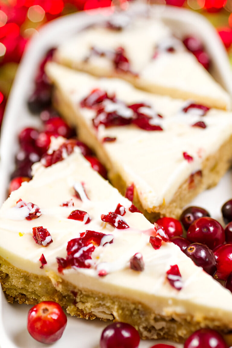 Slices of cranberry cheesecake on a white platter with fresh cranberries