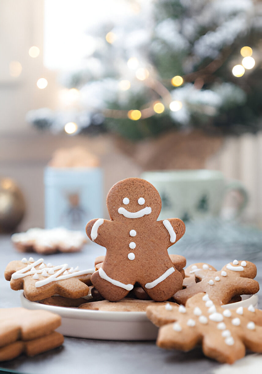 A cheerful gingerbread man cookie surrounded by decorated snowflake cookies, with a festive background of twinkling lights and greenery.