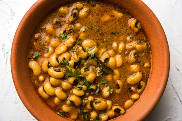 A bowl of black-eyed peas in a flavorful broth, garnished with fresh herbs.