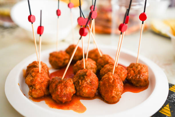 A plate of meatballs garnished with toothpicks and sauce.