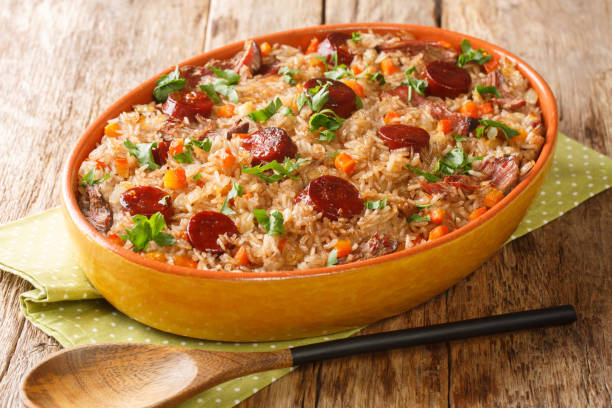 A delicious baked rice dish topped with sliced sausage and garnished with fresh herbs in a vibrant orange casserole dish.