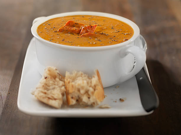 A creamy bowl of soup garnished with herbs and accompanied by bread on a plate.