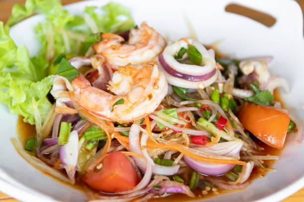 A plate of shrimp salad with fresh vegetables and herbs