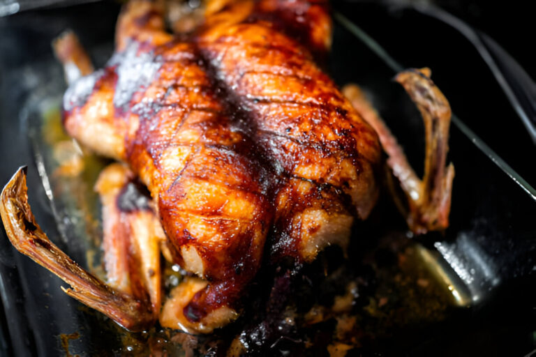 A perfectly roasted chicken with crispy skin placed in a roasting pan.