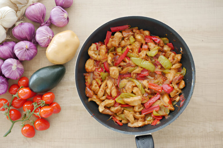 A skillet filled with a colorful chicken stir-fry surrounded by fresh vegetables.