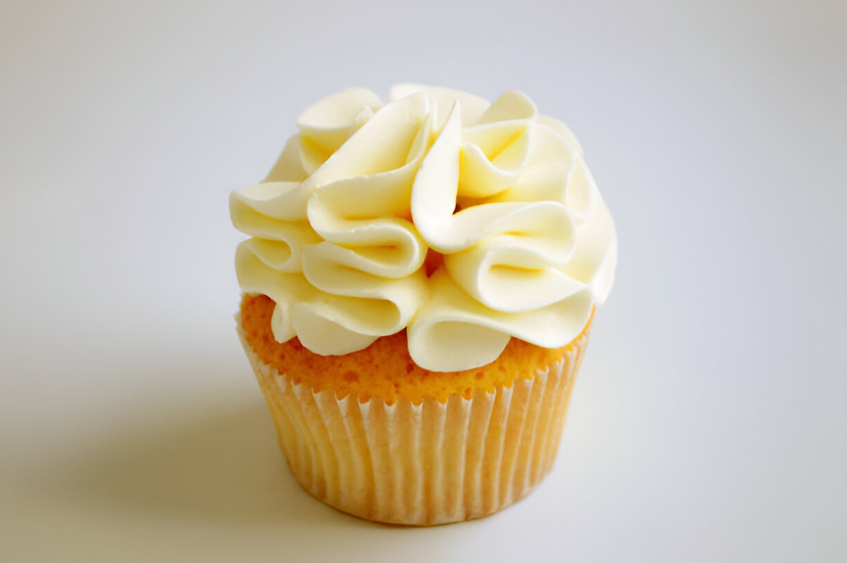 A beautifully decorated cupcake with fluffy white frosting on a light background.