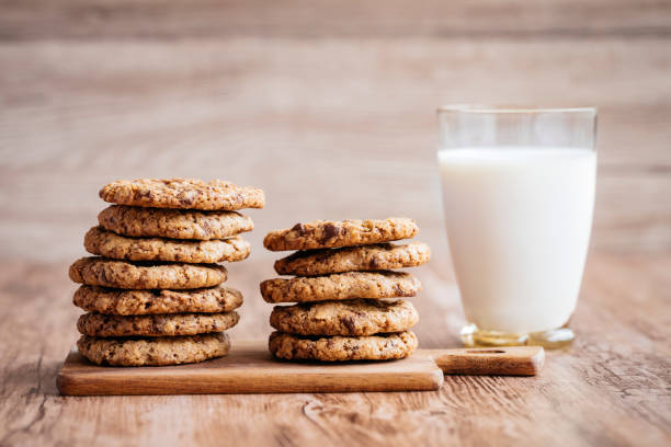 Stack of oatmeal cookies on a wooden board next to a glass of milk