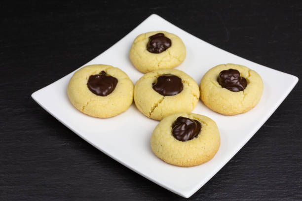 A plate of cookies featuring a round shape with a chocolate center, placed on a white dish.