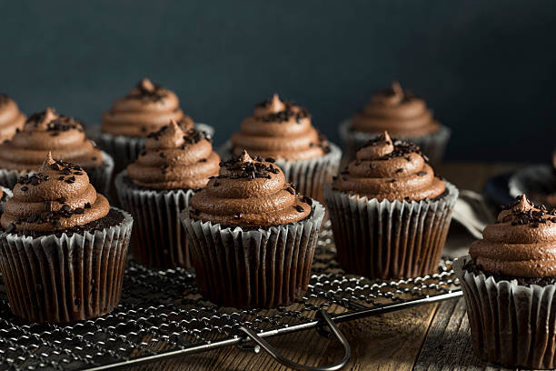 A plate of chocolate cupcakes with rich frosting and chocolate shavings on top.