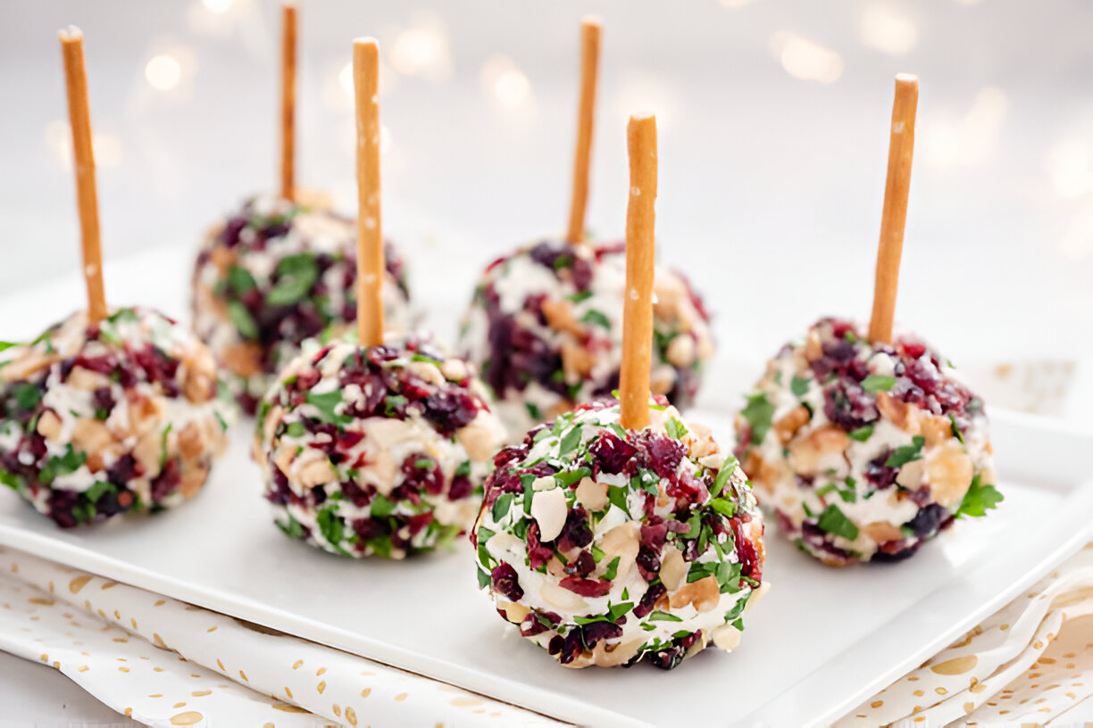 Colorful appetizer cheese balls coated with herbs and nuts on sticks