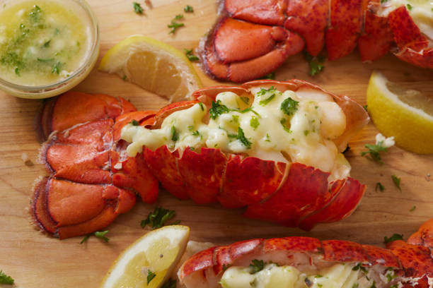 Plated lobster with melted butter and garnished with parsley, served with lemon wedges.