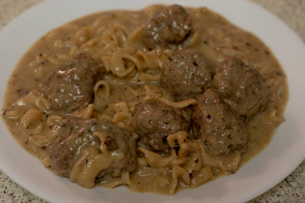 A plate of meatballs served with egg noodles in a creamy brown sauce