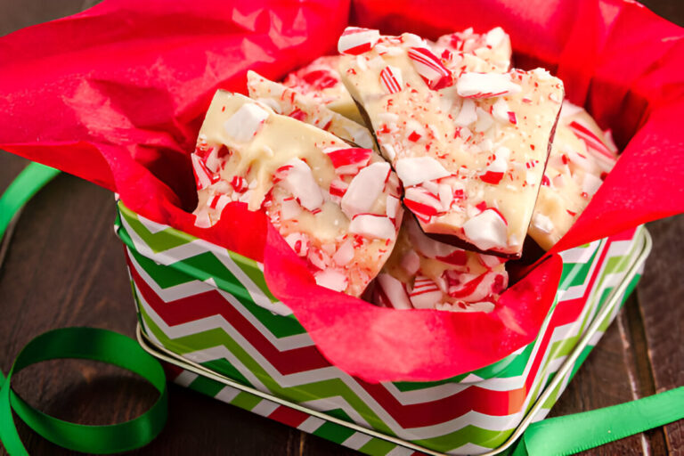 Holiday-themed gift box filled with peppermint bark dessert, wrapped in red tissue paper.