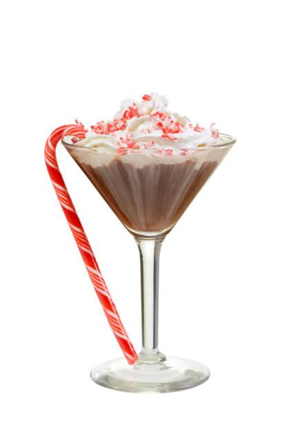 A festive cocktail in a martini glass topped with whipped cream and crushed peppermint, accompanied by a candy cane.