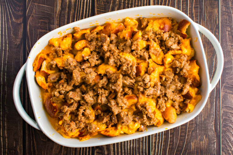 A baked casserole dish filled with a mixture of cheese, sausage, and sweet potatoes.