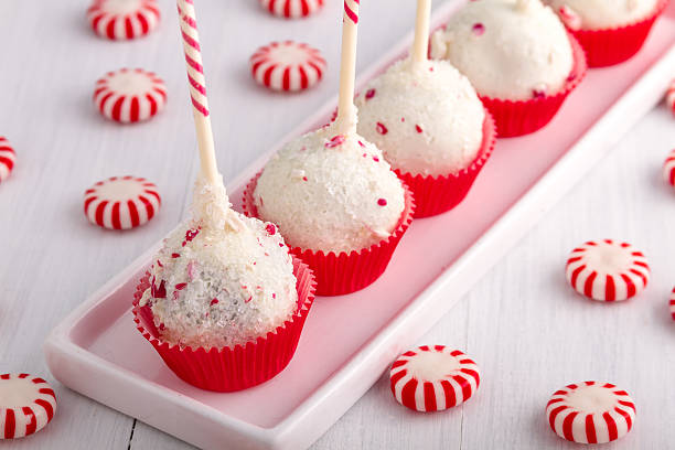 Colorful cake pops with peppermint decorations on a white platter, surrounded by peppermint candies.