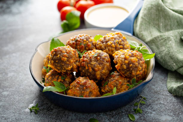 A bowl of colorful, healthy lentil balls garnished with greens, served with a dipping sauce.