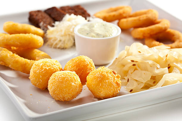 A platter of various fried foods including golden cheese balls, onion rings, a saucy dip, and coleslaw.