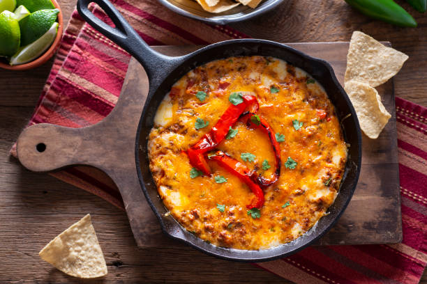 A delicious skillet dish featuring melted cheese and red peppers, garnished with cilantro, served with tortilla chips.