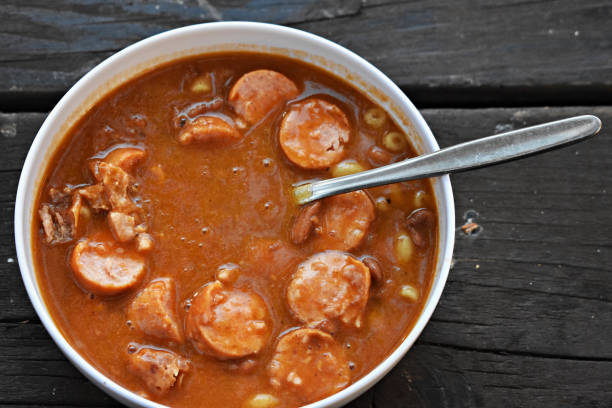 A bowl of hearty sausage stew on a wooden table