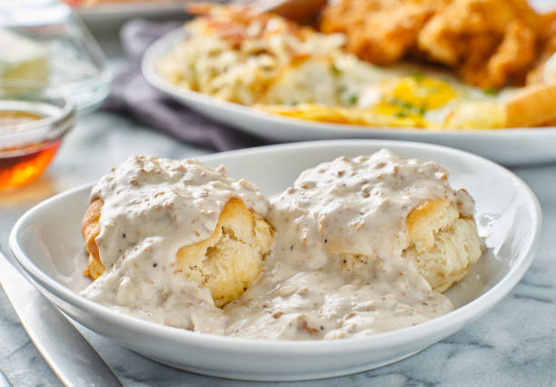 Two warm biscuits covered in creamy sausage gravy served on a white plate