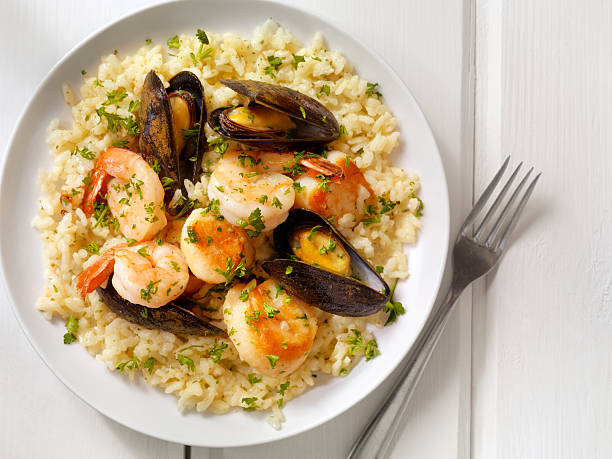 Delicious seafood dish featuring shrimp and mussels over rice, garnished with parsley.