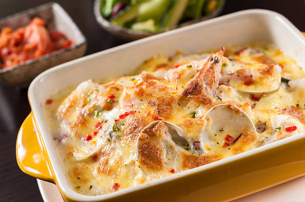 Baked creamy seafood dish with layers of fish and melted cheese served in a yellow baking dish.