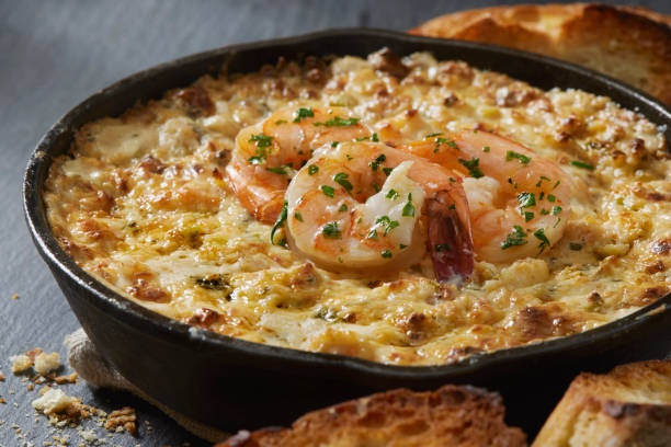 A savory baked shrimp dish served in a cast iron skillet with toasted bread on the side.