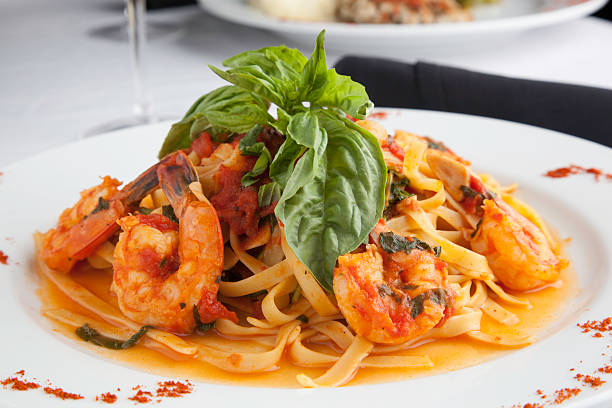 A plate of shrimp linguine topped with fresh basil and a tomato-based sauce