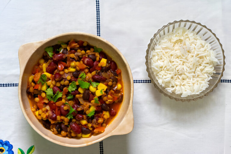 A bowl of colorful mixed bean and vegetable stew with a side of white rice