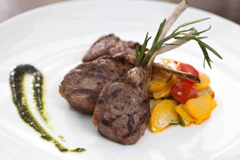 Grilled lamb chops served with sautéed vegetables and a drizzle of sauce.