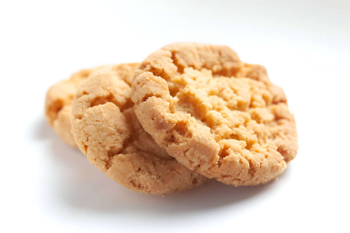 Three golden brown peanut butter cookies stacked on a white background.