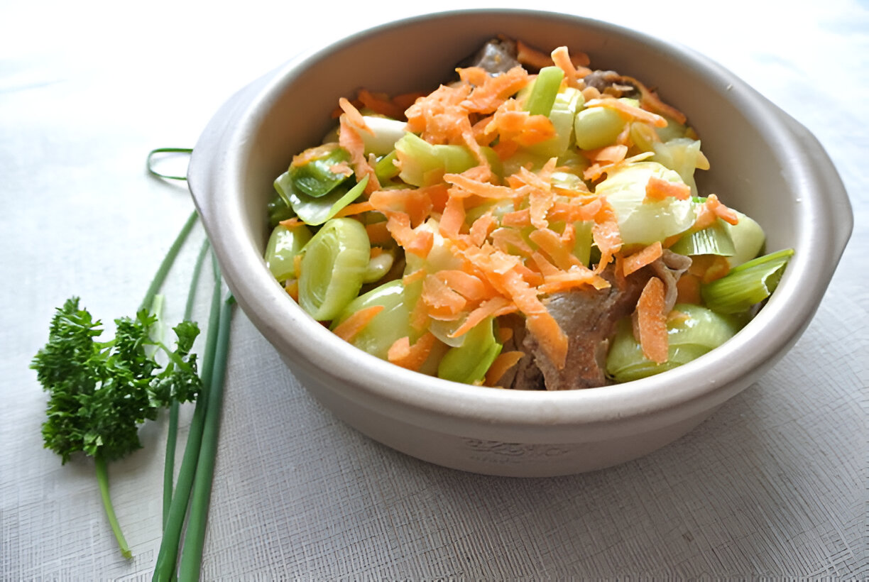 A bowl of stir-fried vegetables including green onions, celery, and shredded carrots, garnished with herbs.