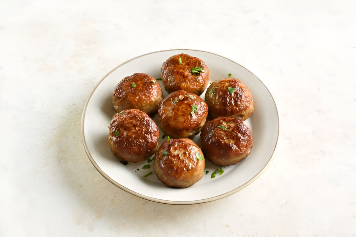 A plate of golden brown meatballs garnished with fresh parsley