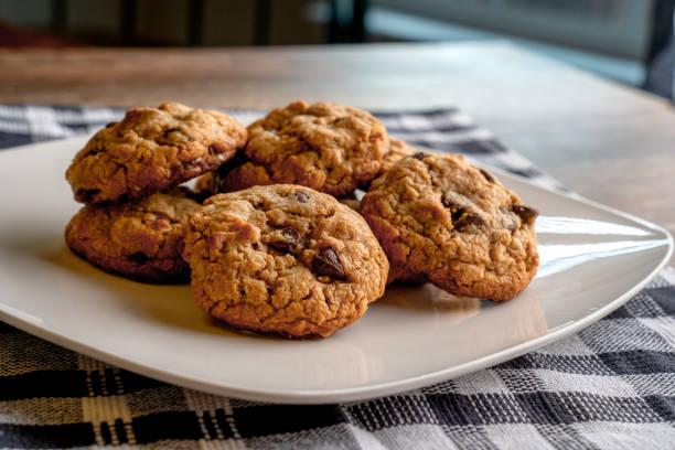 A plate of freshly baked chocolate chip cookies on a checkered tablecloth.