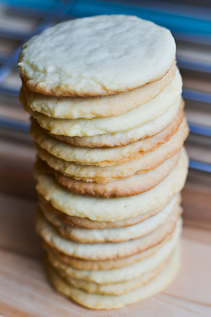 A tall stack of golden-brown cookies on a wooden surface.