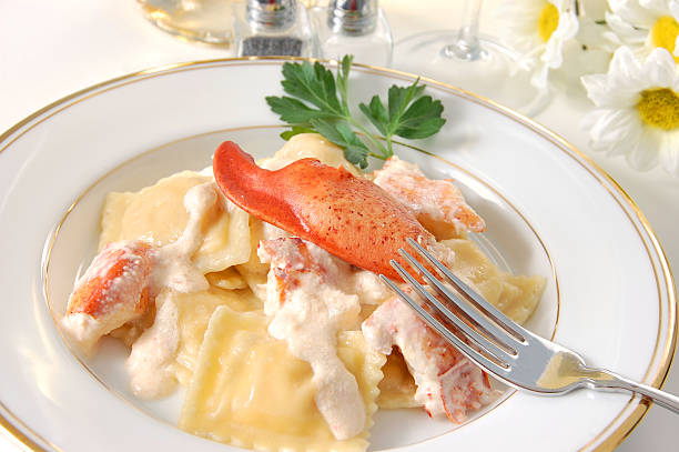 Plate of lobster ravioli topped with a lobster claw in a creamy sauce, garnished with parsley