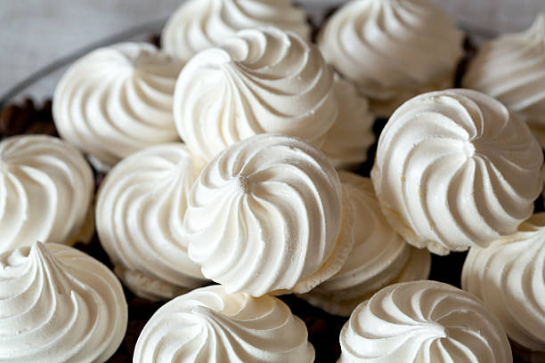 A close-up view of beautifully piped white meringue cookies arranged in a decorative manner.