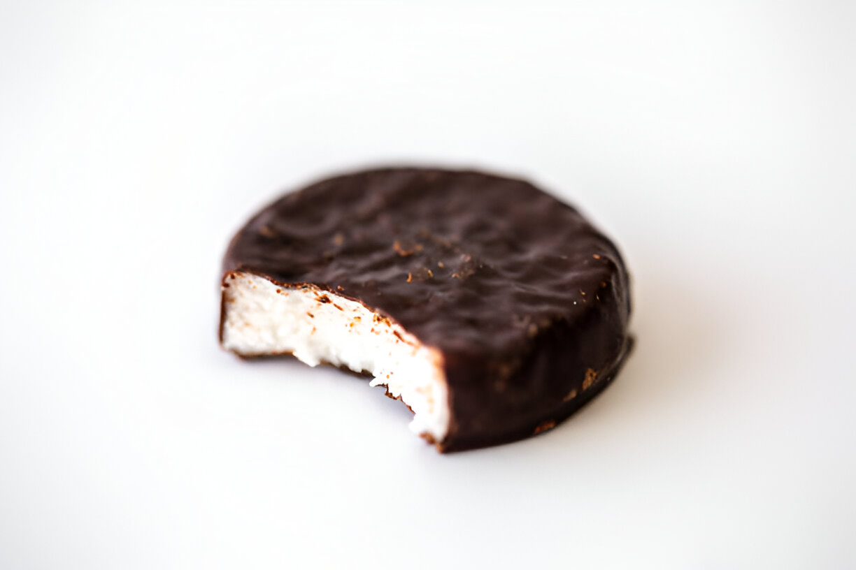 A chocolate-covered treat with a bite taken out of it, revealing a creamy interior.