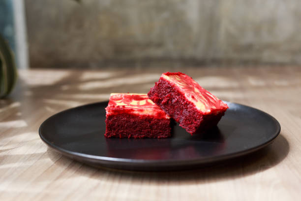 Two red velvet brownies on a black plate