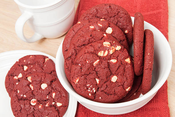 A bowl of red velvet cookies with white chocolate chips, placed on a table with a red cloth.