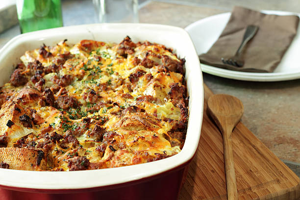 A baked dish of savory bread pudding topped with cheese and herbs, served in a red casserole dish.