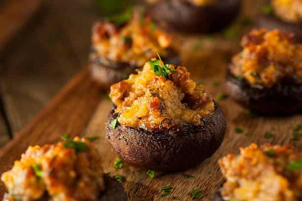 Stuffed mushrooms topped with herbs on a wooden platter